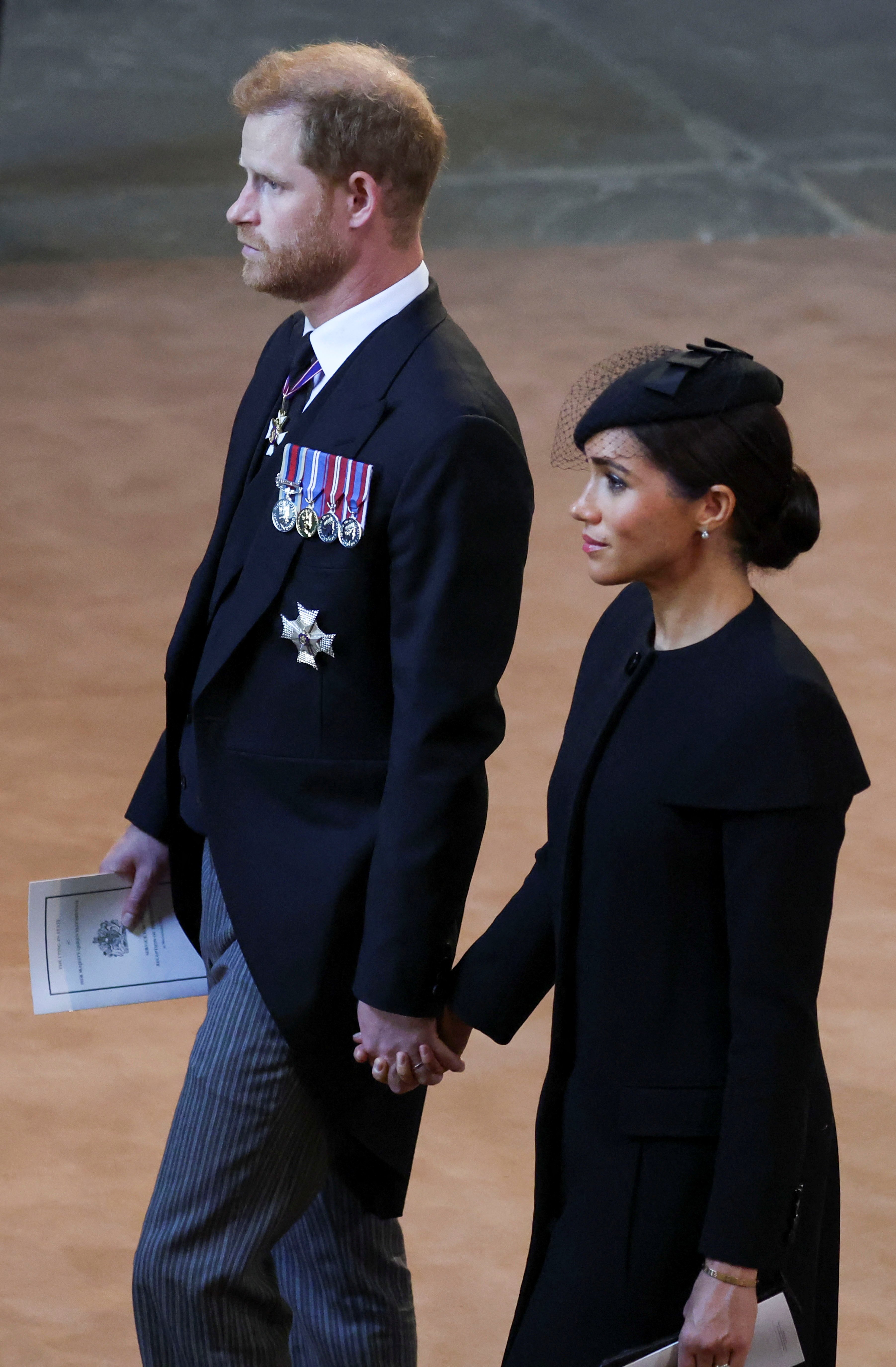 Prince Harry, Duke of Sussex and Meghan, Duchess of Sussex walk as the procession carrying the coffin of Britain's Queen Elizabeth arrives at Westminster Hall from Buckingham Palace for her deposition, on September 14, 2022 in London, UK |  Source: Getty Images 